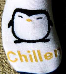 A photograph of a sock that has a picture of a penguin and the word Chillen.